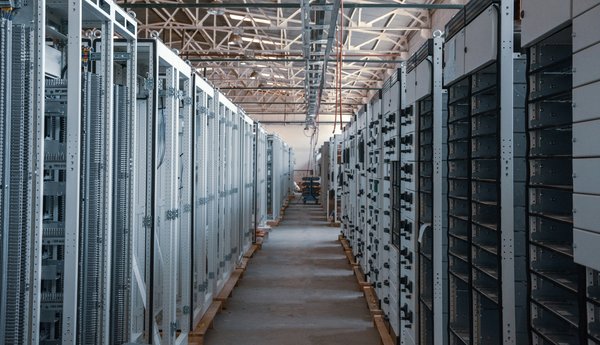 A modern data center aisle with rows of server racks illuminated by blue and white LED indicators, representing automated bare metal infrastructure