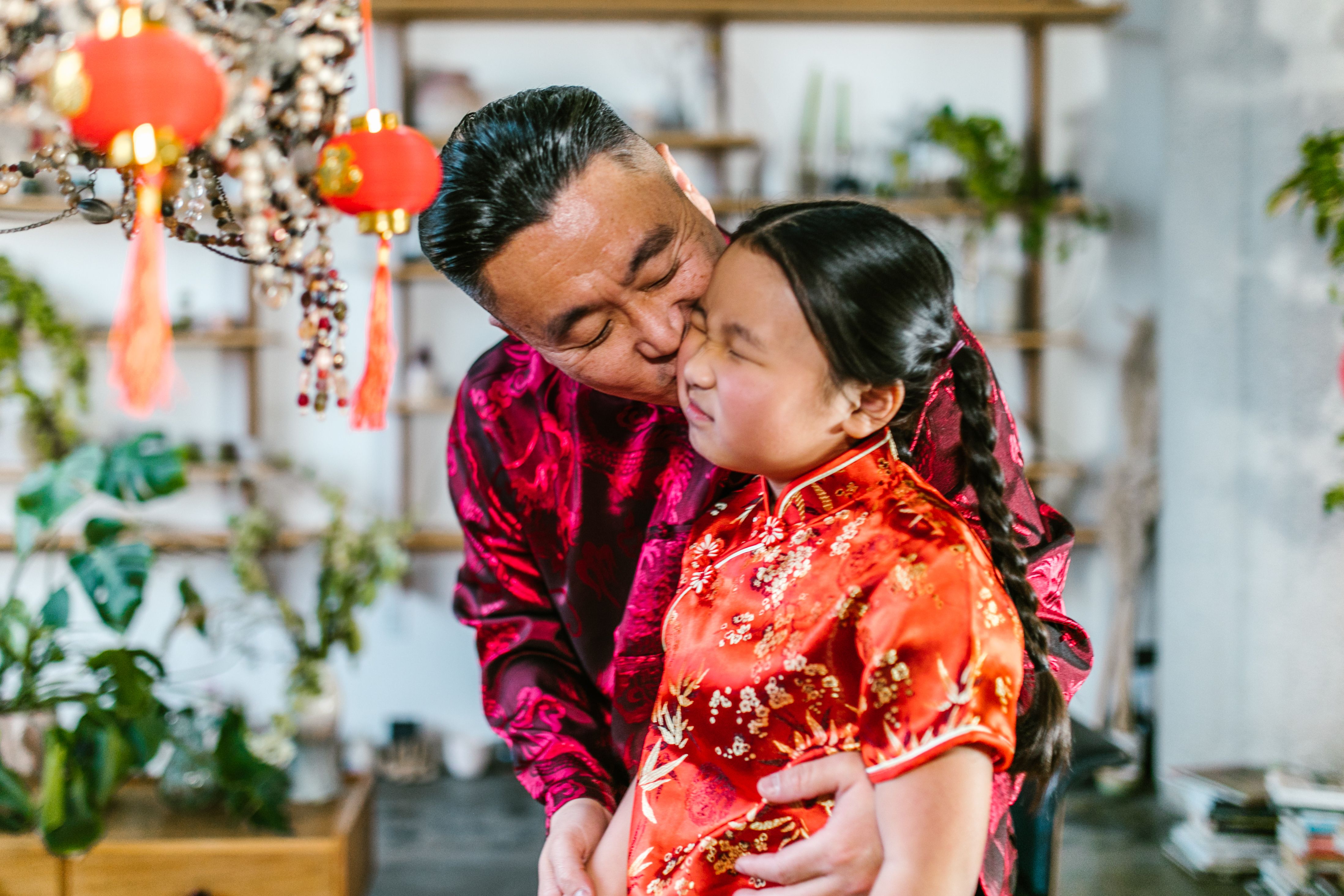 Father kissing daughter's cheek while wearing traditional clothes, representing unconditional love across generations