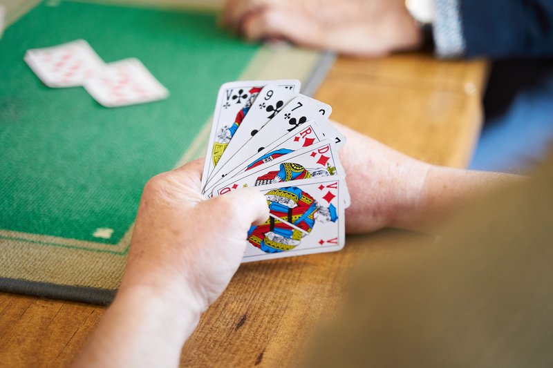 Close-up of two hands exchanging playing cards across a table, symbolizing partnership and coordination between teammates