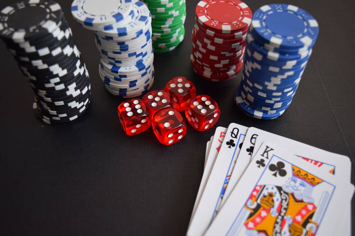 A vibrant overhead shot of playing cards, casino chips, and dice spread across a green felt table