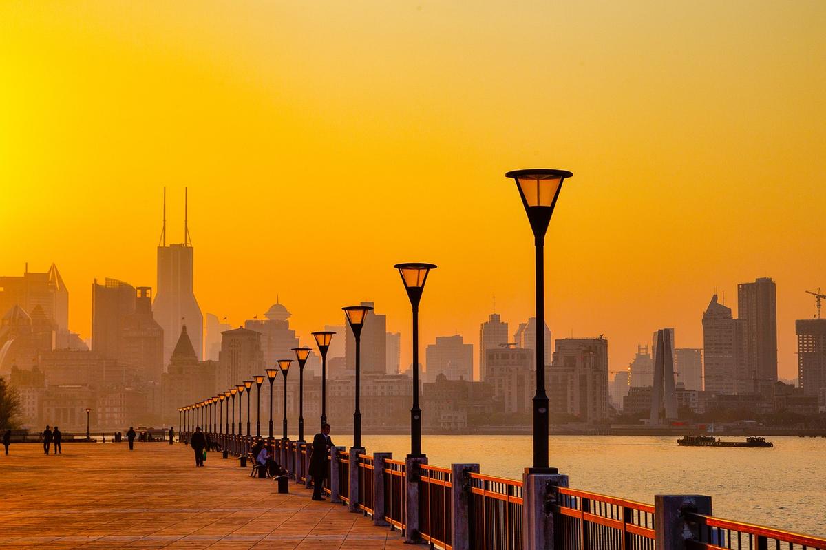 A wide aerial view of Shanghai's Pudong skyline and the Huangpu River at dusk, representing the city's housing market at a valuation crossroads