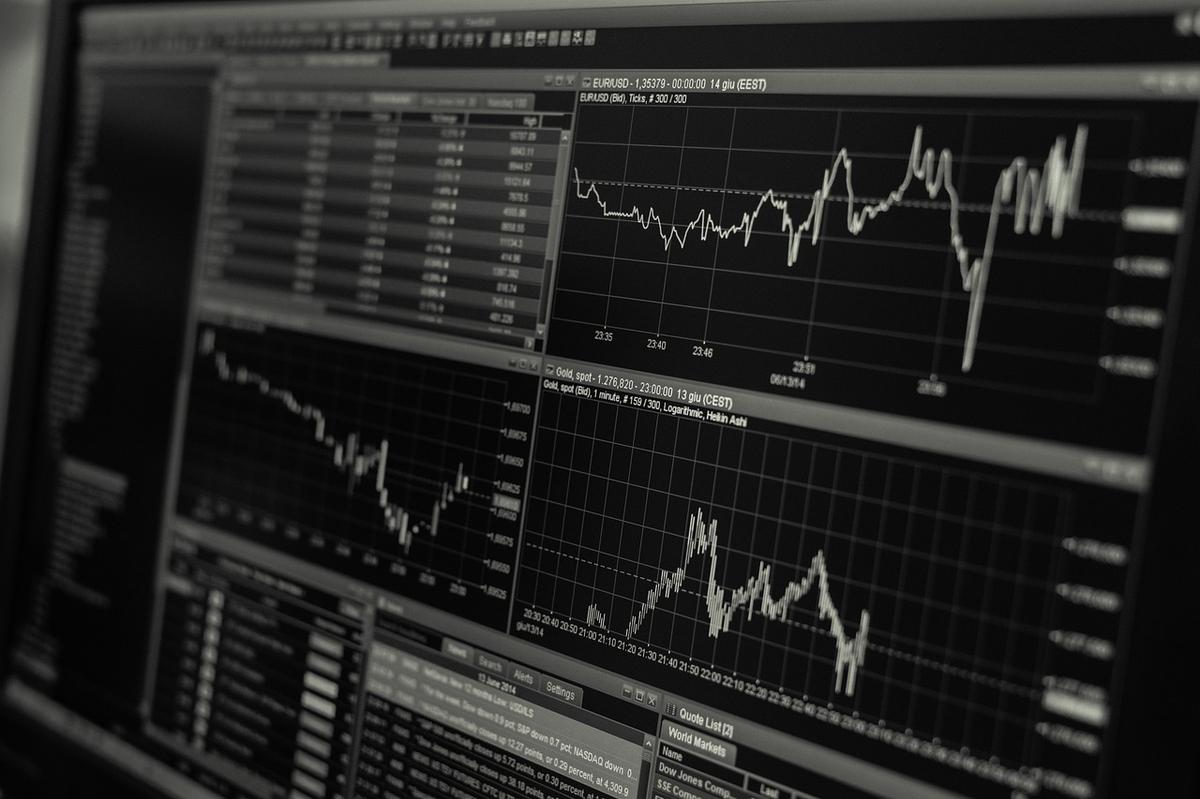 A stock trading monitor displaying financial data charts and market numbers on a dark screen