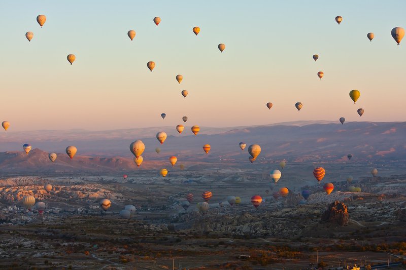 Colorful hot air balloons floating over Cappadocia fairy chimneys at sunrise, Turkey
