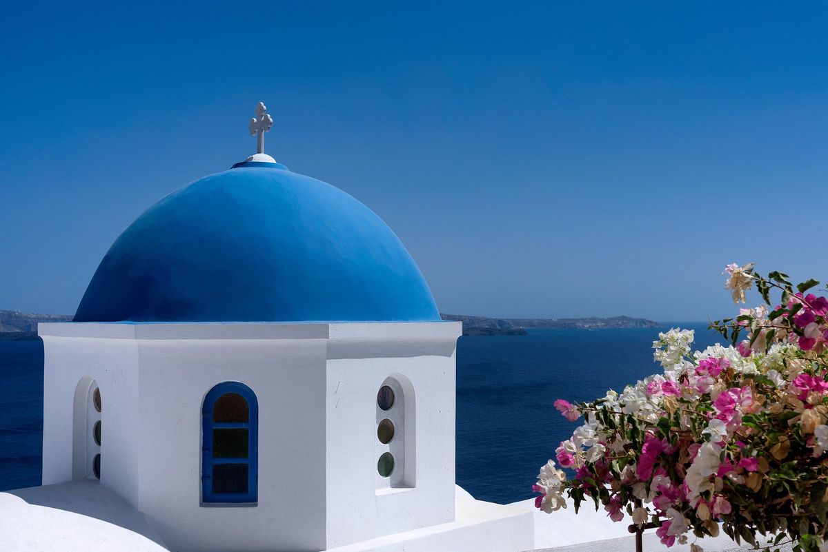 Iconic blue-dome church overlooking the Santorini caldera at sunset, Greece